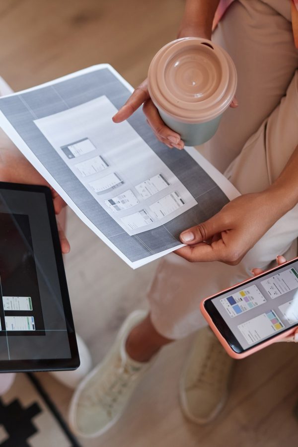 Female business team discussing web design project and holding smartphones